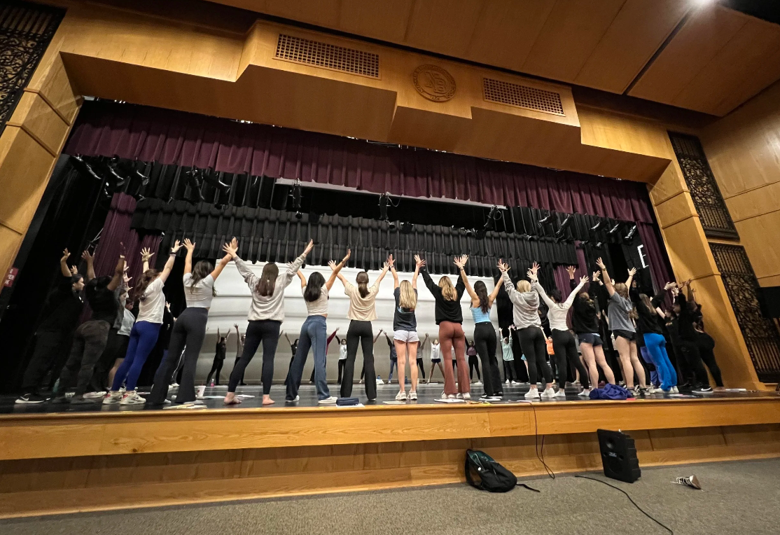 Workshop participants together onstage, raising their arms